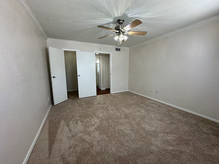 Spacious bedroom with plush carpet, ceiling fan, and ample natural light. Spacious bedroom with plush carpet, ceiling fan, and ample natural light.