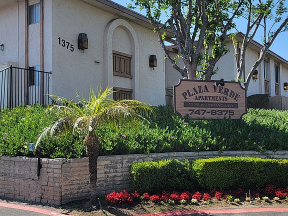 Gated front enterance with lush gardens at Plaza Verde Apartments in Escondido, California.