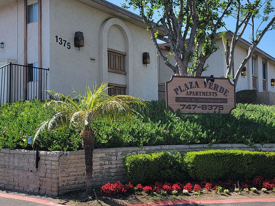 Gated front enterance with lush gardens at Plaza Verde Apartments in Escondido, California.