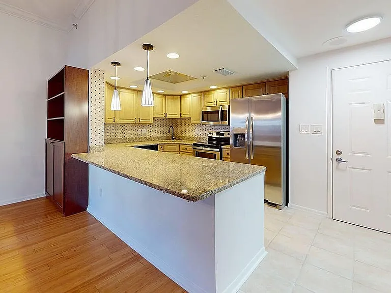 Elegant apartment kitchen with granite countertops, stainless steel appliances, and warm wooden cabinetry.