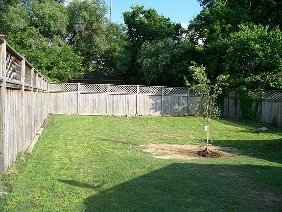 Large, privacy fenced back yard with storage buildings.