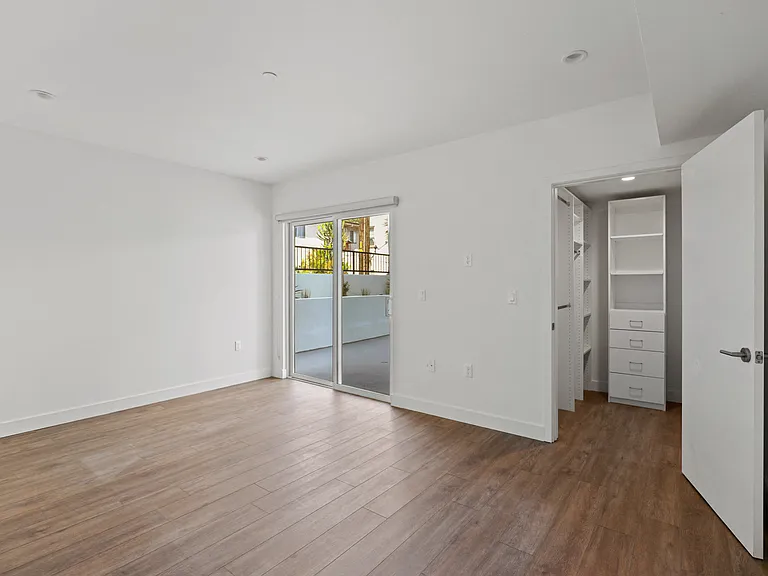Bedroom with Walk-In Closet with Built-In Organizers, Vinyl Flooring, and Patio
