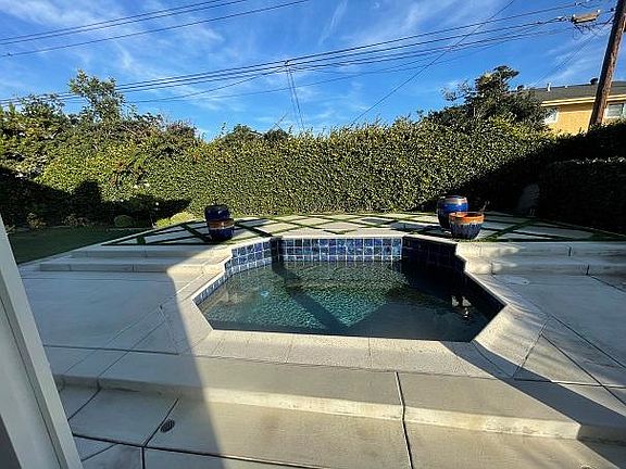 Backyard oversized jacuzzi and raised patio area