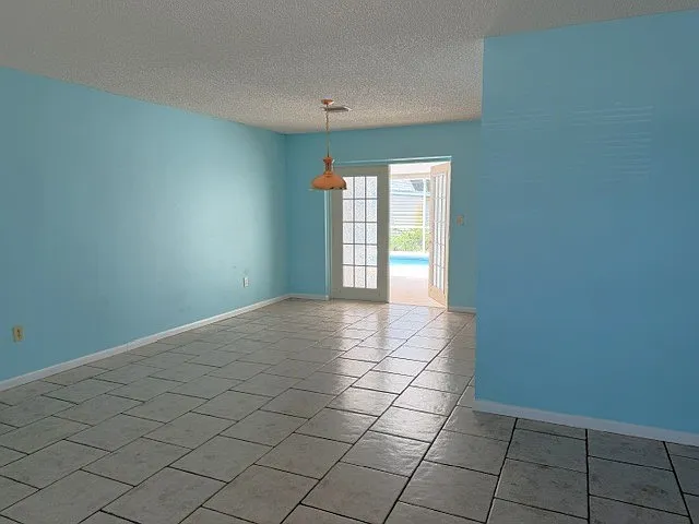 Living room looking into dining area. The French doors lead to the lanai and pool. The paint in all rooms is in excellent condition, but the tenant can repaint if the beach vibe isn't your style.