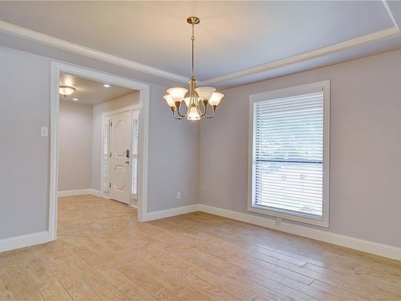 The dining room looking out to the entry.  The windows look out to the front yard.  Crown molding and wood like porcelain floor.