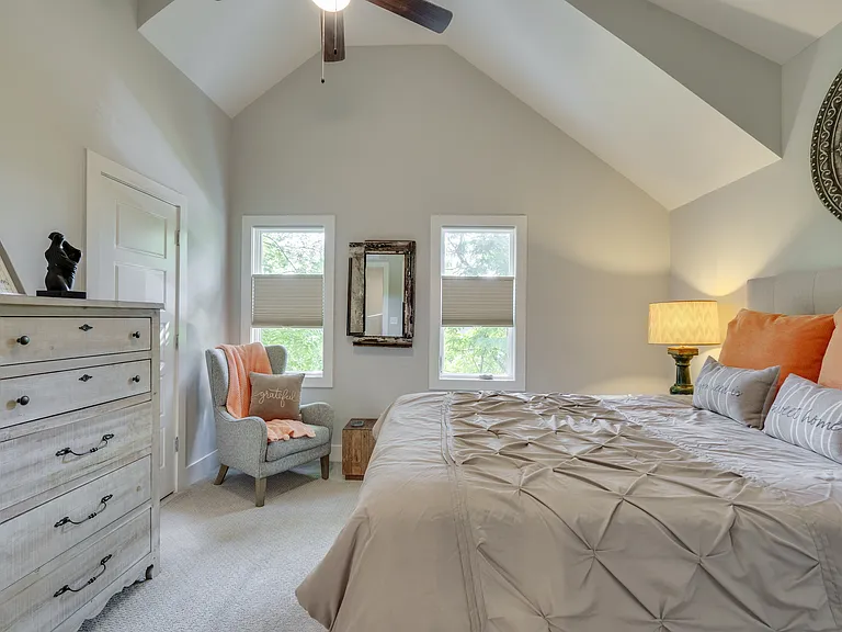 Beautifully appointed second ensuite bedroom featuring a plush pillow-top queen bed, large windows with top-down/bottom-up blackout shades, a walk-in closet, spacious dresser, comfortable seating, USB charging ports, and a private ensuite bathroom.