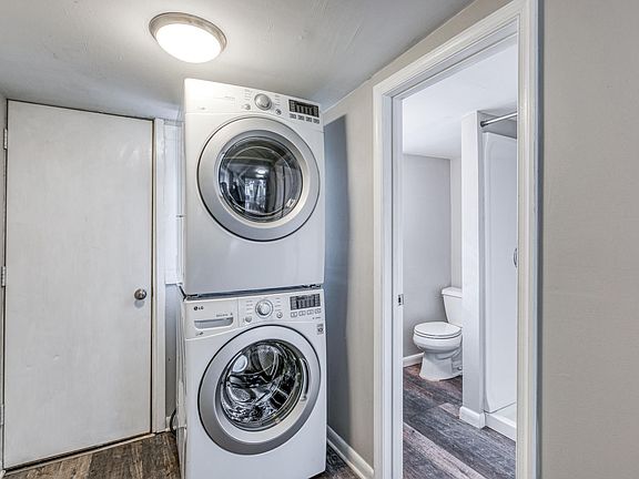 Back door to patio, stacked washer/dryer, and first floor full bath with stall shower
