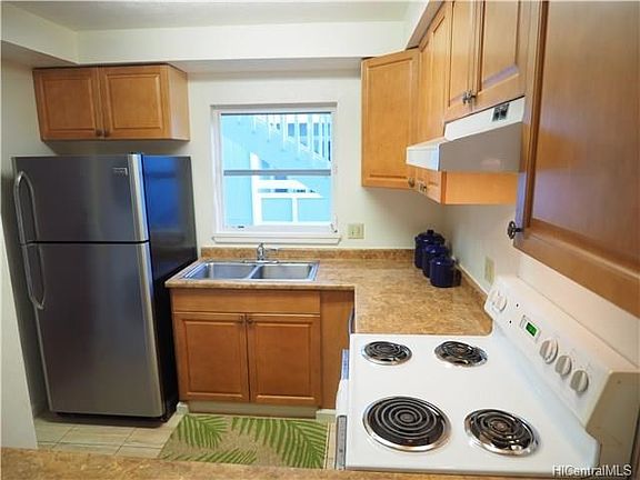 Another view of the kitchen with stainless steel refrigerator and dishwasher.