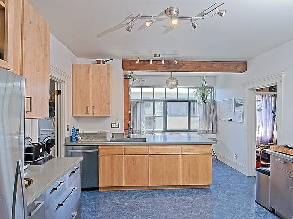 Large chefs kitchen with big windows, stainless appliances and large peninsula/ island with a breakfast bar.