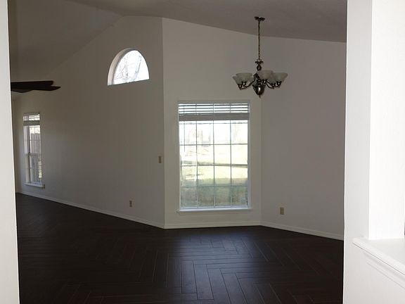 Walking in front door. Large vaulted living room to the left, open dining area visible ahead, and kitchen off to the right.