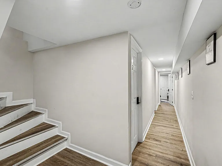 Wide interior hallway with stair access, recessed lighting, and durable wood-look flooring connecting multiple rooms.