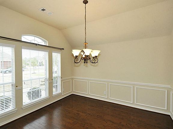 Across from the study is this formal dining room with wall to wall hard wood flooring, large windows, and more beautiful white trim work.