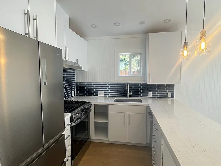 Chef's kitchen with large sink, dishwasher, gas range, range hood, and french door fridge/freezer.
