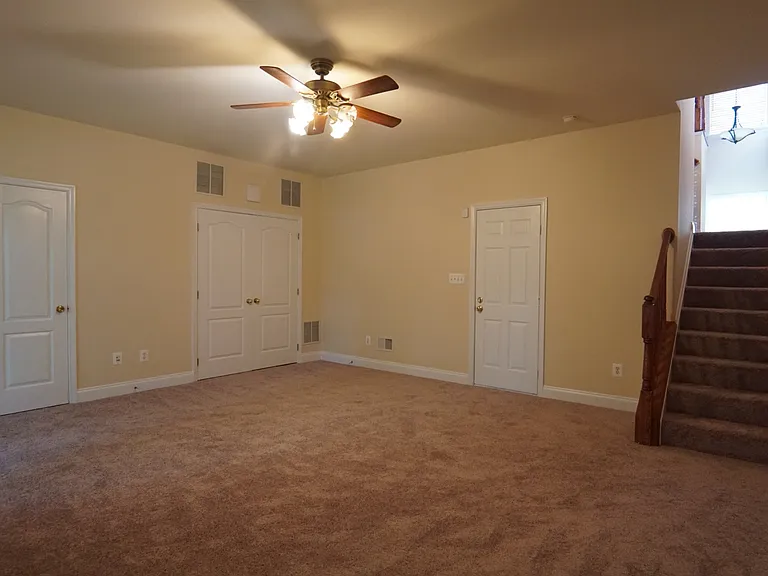 View back toward stairs to main living level from basement. Doors (left to right) to half bath, utility, and garage.