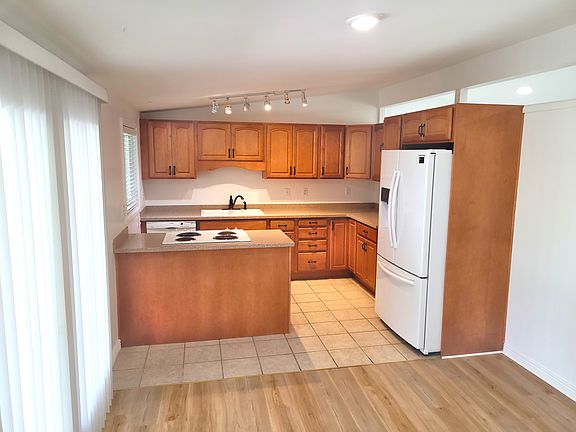 Kitchen with maple cabinets and lots of storage space, quartz countertops, fridge, dishwasher, stove and oven