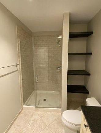 Bathroom with tile and granite. Shelving for additional storage.