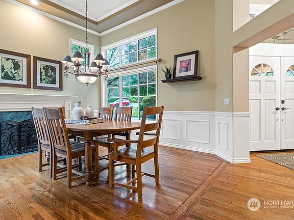 The grand formal dining room with tall ceiling height with double crown moldings, wainscoting and marble surround wood burning fireplace. >