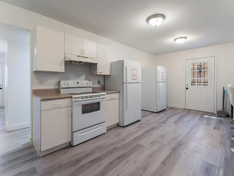 Efficient kitchen setup: electric stove with FireStop accompanied by two refrigerators for ample storage and meal prep.