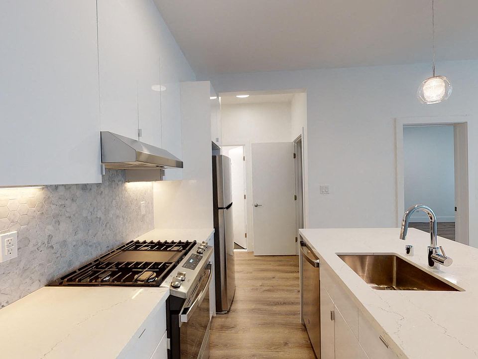 Kitchen with multiple cabinets, refrigerator, stove, range hood, and sink