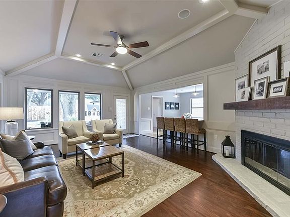 Large and open living room with gleaming wood floors, an abundance of windows, vaulted ceilings and wood burning fireplace.