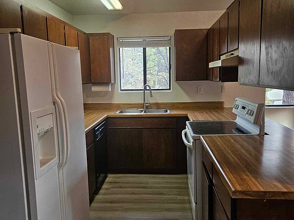 Galley kitchen with electric range, dishwasher, refrigerator, & lots of cupboard storage