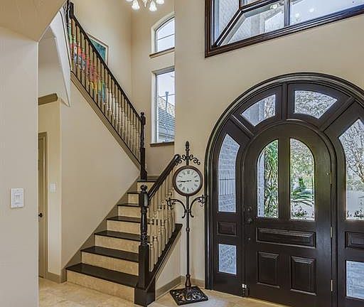 2 STORY FOYER WITH CUSTOM TILED COMPASS ROSE AND BEAUTIFUL ARCHED DOOR FRAMED BY ARCHED TRANSOM WINDOWS.