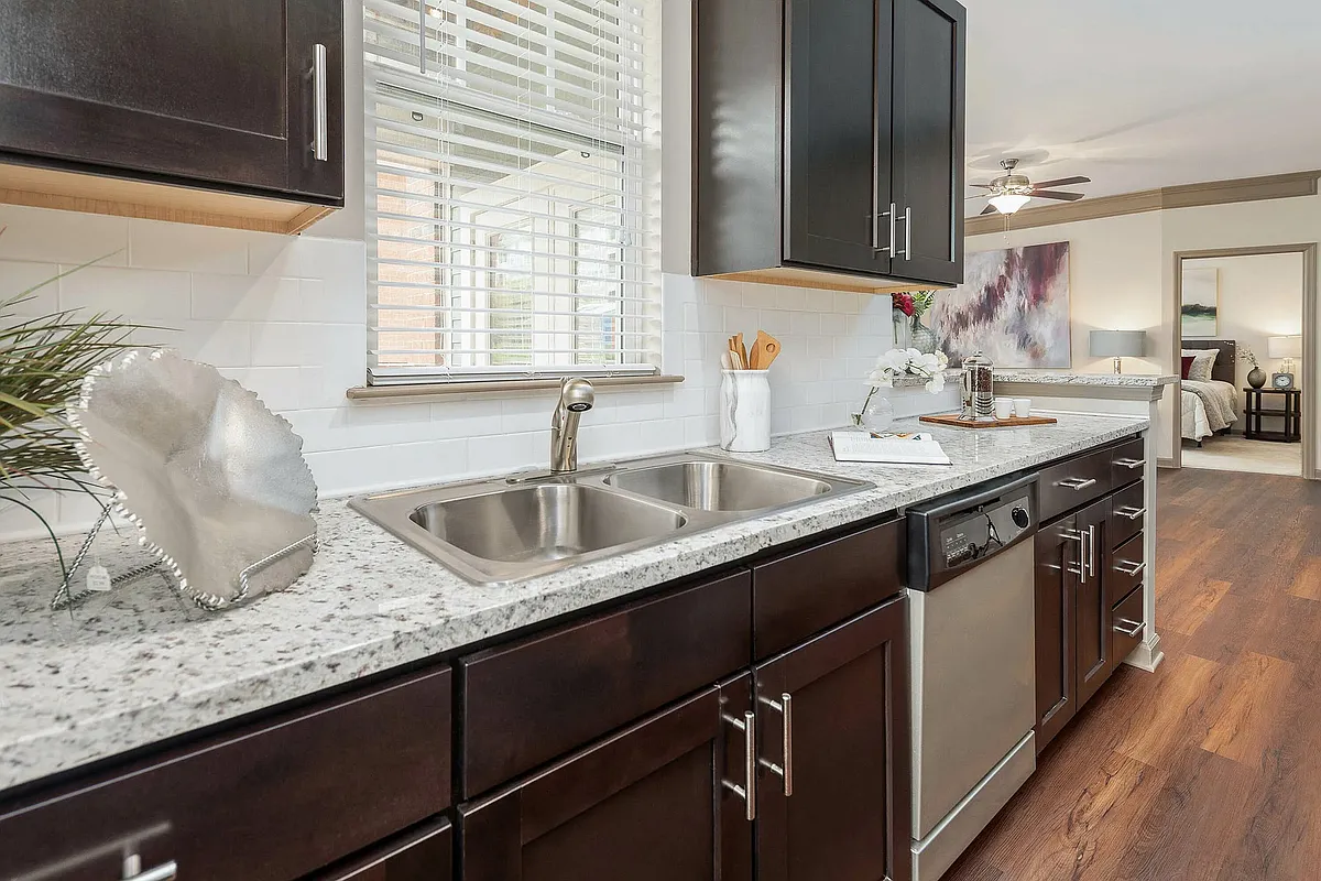 Modern apartment kitchen with granite countertops, stainless steel appliances, and rich cabinetryopen-concept living in Charlotte. - The District