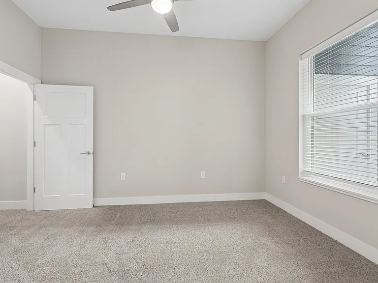 Carpeted bedroom with ceiling fan of a Tiffany Flats apartment home.