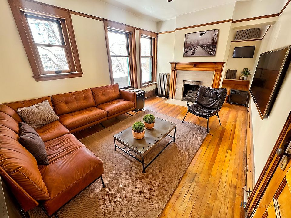 Chic living room featuring a luxurious brown leather sectional, sleek armchair, and a cozy fireplace with contemporary decor.