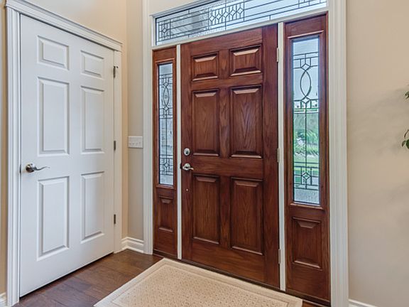 The front entry welcomes you with hand scraped wood flooring, vaulted ceiling, decorative transom and radius windows and a deep coat closet with convenient access to controls for the exterior electrical outlets.