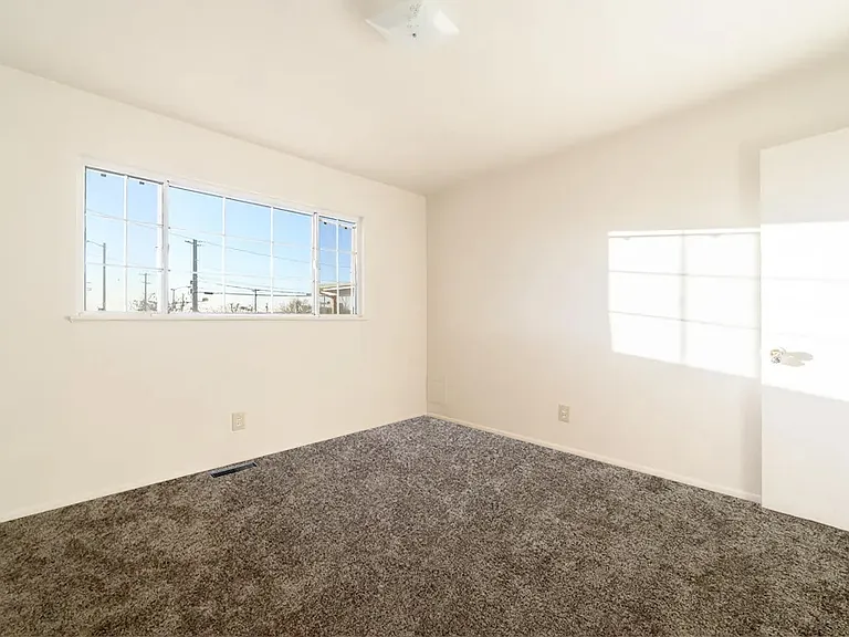 Bedroom 2 features a large picture window that fills the room with natural light, a spacious walk-in closet, updated carpeting, modern light fixtures, and upgraded electrical outlets, creating a comfortable and inviting retreat.