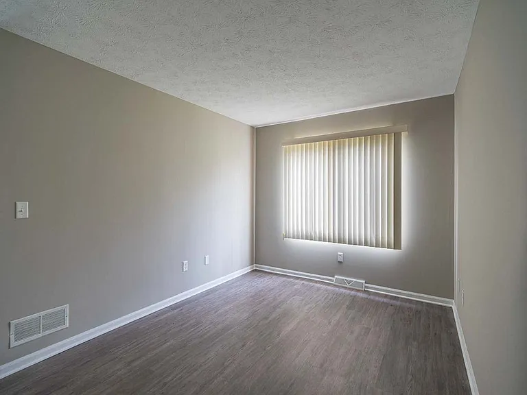 View of typical primary bedroom with large windows and faux plank flooring