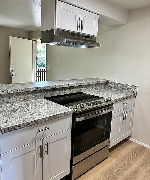 Modern kitchen with sleek granite countertops, contemporary white cabinetry, and stainless steel appliances.