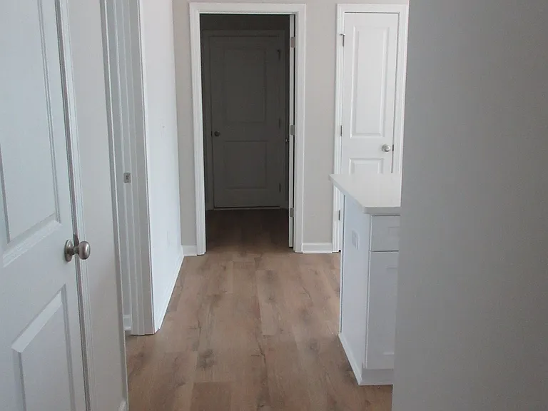 View of hall from bedrooms leading to kitchen on right and laundry room straight ahead