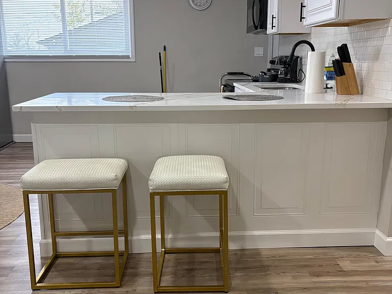 Kitchen features a wide breakfast bar with seating, white cabinetry, subway-tile backsplash, and ample counter space.