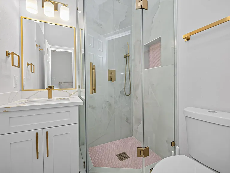 Updated bathroom with a glass-enclosed shower, designer tile, and a vanity with ample cabinet storage and modern fixtures.