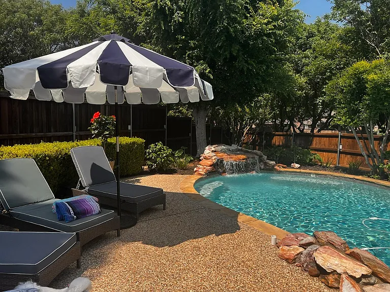 Large private backyard with pool, waterfall, and mature landscaping