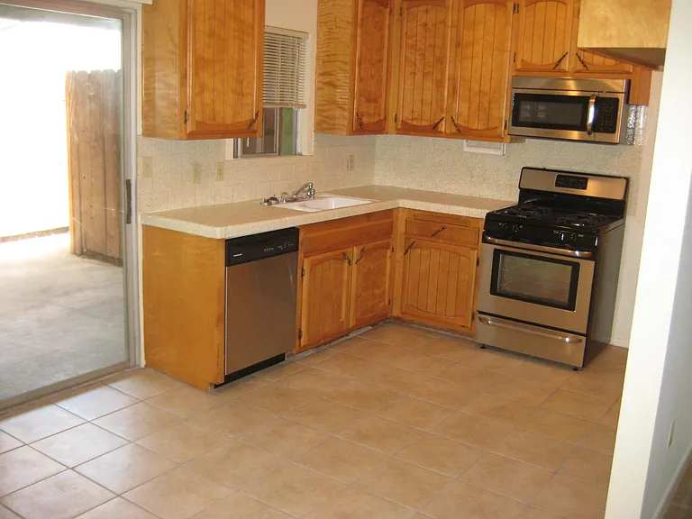 Kitchen with newer appliances and tile flooring, refrigerator is provided.