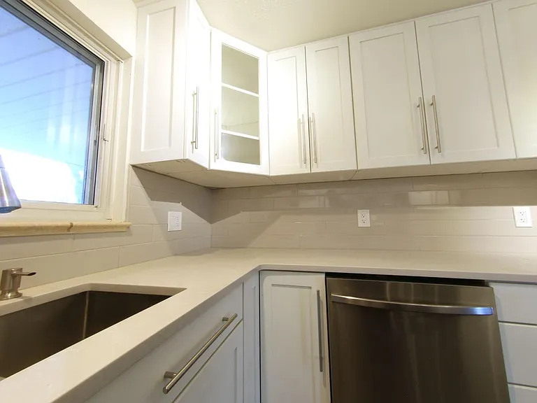 The Quartz Counters are a dream to have in a kitchen as they are clean and durable. Note the glass corner cabinets and built-in soap dispenser.