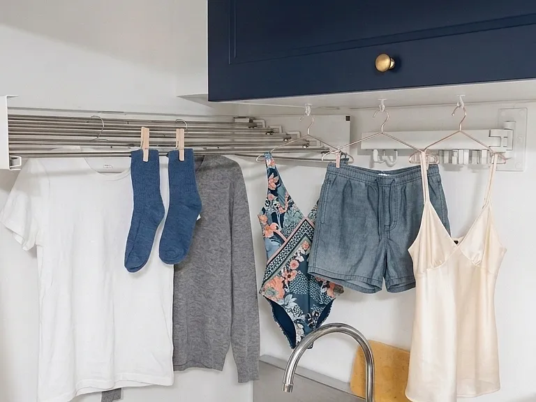 Wall-mounted, built-in, expandable clothes drying racks above the sink in the laundry closet