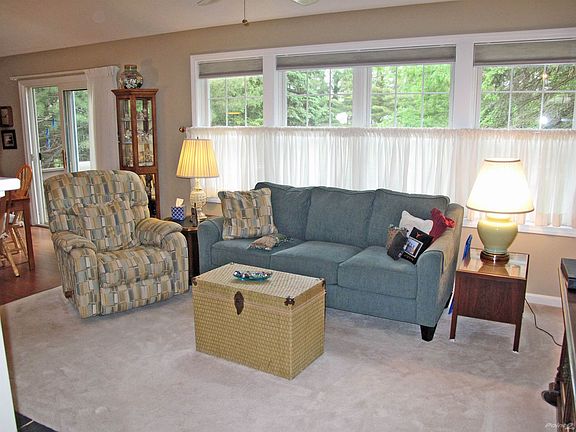 The Living Room is open and bright, featuring a wood-burning fireplace and a cathedral ceiling.