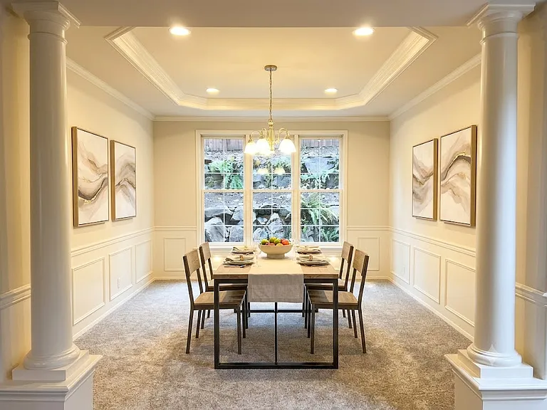 Sophisticated dining space defined by a columned entry, classic wainscoting, and a tray ceiling, perfect for hosting elegant gatherings (computer staged)