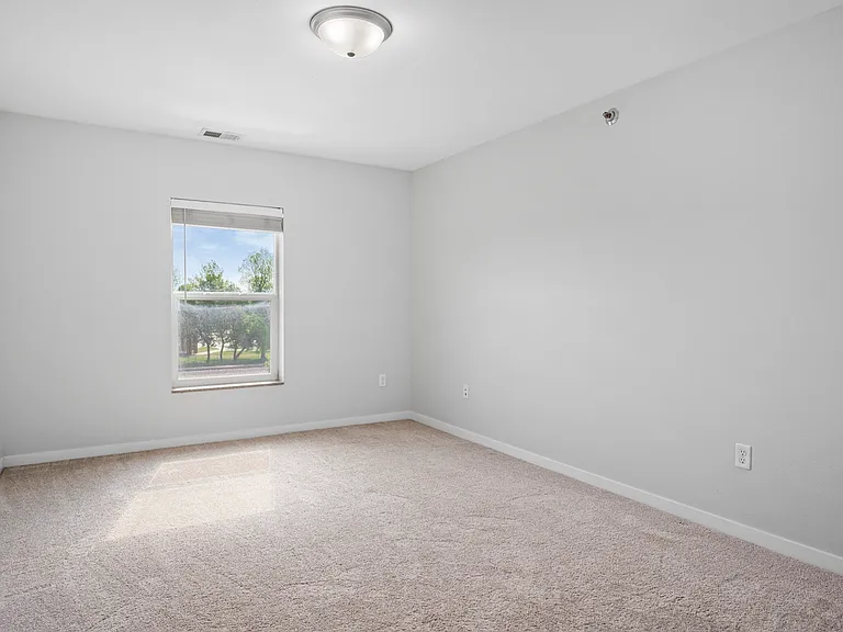 Bright and airy bedroom with soft carpet flooring and a window view, offering a serene atmosphere. Bright and airy bedroom with soft carpet flooring and a window view, offering a serene atmosphere.