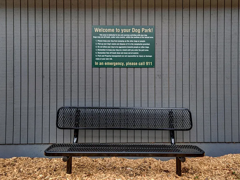 a bench in front of a wall with a sign on it Sunset Station Apartments Portland Oregon