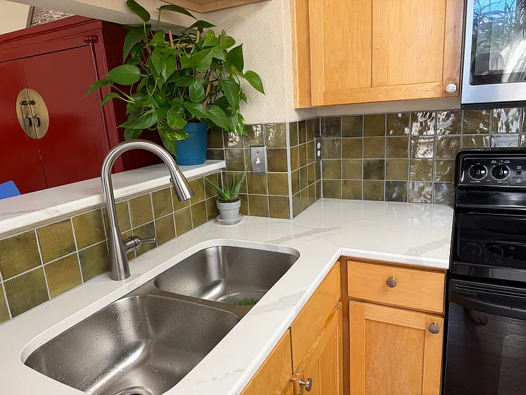 Kitchen with new quartz countertops, tile backsplash, sink, faucet and microwave. Large stainless steel fridge. Technically is the size of an "eat-in" kitchen.