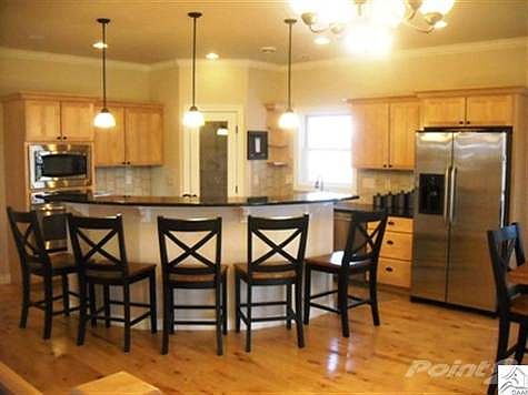 Open kitchen/ dining area with granite countertops and stainless steel appliances.
