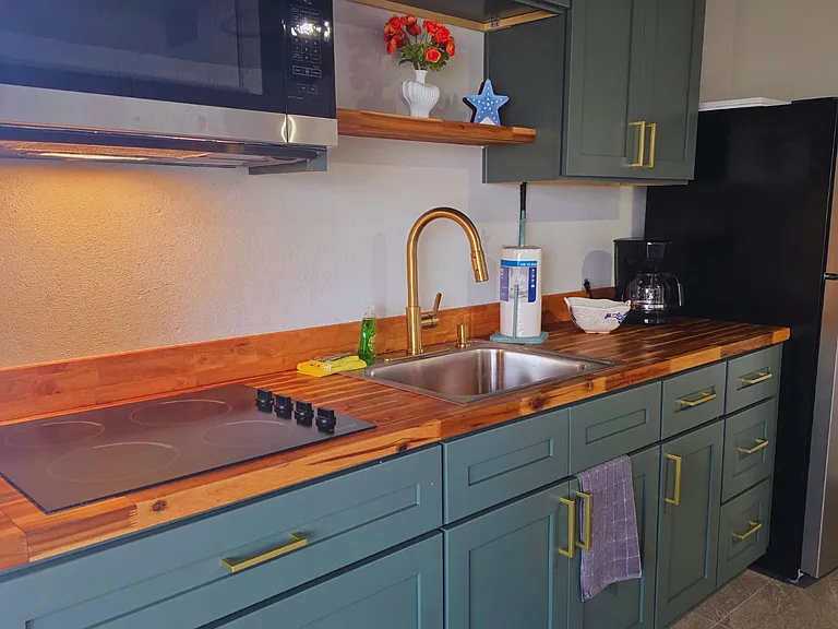 Modern kitchen with cabinets, coffee maker, microwave and large fridge.