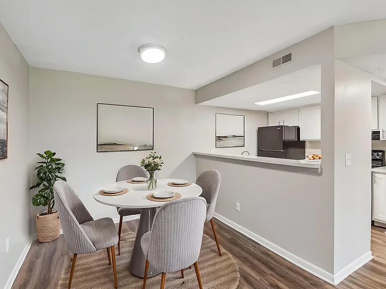 Chic dining area with elegant table setting beside a sleek, modern kitchen featuring stainless steel appliances and stylish artwork.