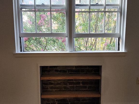 Exposed-brick bookcase and view of the crepe myrtles.