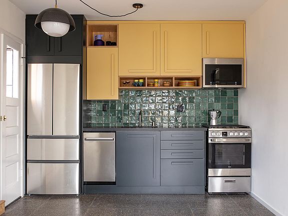 The kitchen with gas range, built-in microwave and exhaust hood, dishwasher, and refrigerator/freezer